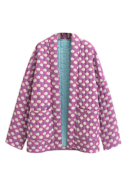 Woman wearing a pink quilted mid-length jacket with a white floral pattern, styled open over a white top and light blue jeans.