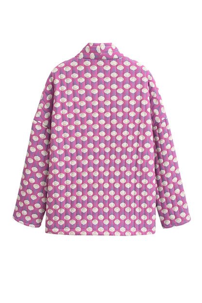 Woman wearing a pink quilted mid-length jacket with a white floral pattern, styled open over a white top and light blue jeans.
