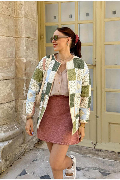 A woman wearing a quilted patchwork jacket with floral and solid panels, styled over a beige shirt and pink textured mini skirt.