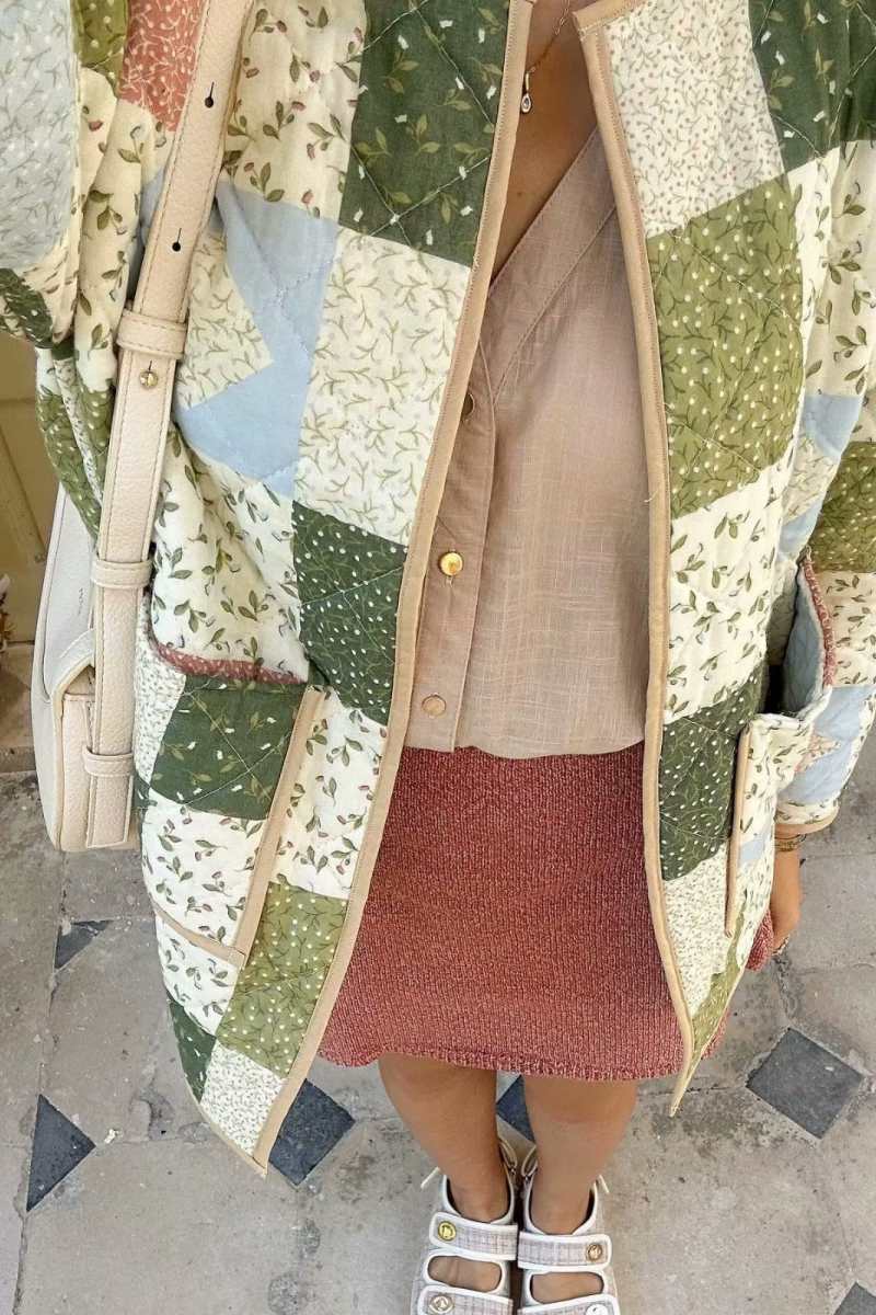 A woman wearing a quilted patchwork jacket with floral and solid panels, styled over a beige shirt and pink textured mini skirt.