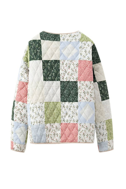 A woman wearing a quilted patchwork jacket with floral and solid panels, styled over a beige shirt and pink textured mini skirt.