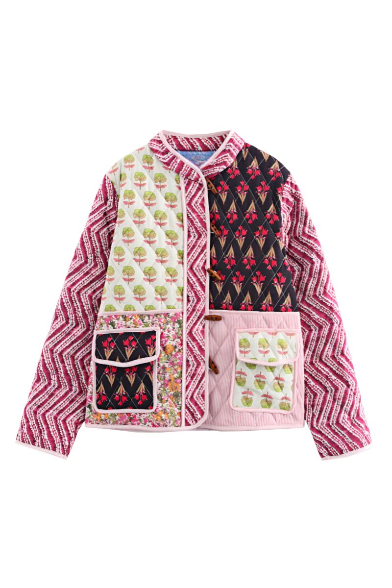 Woman wearing a quilted patchwork jacket featuring mixed floral and chevron prints, paired with a white maxi skirt.