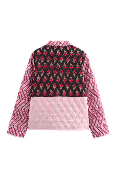Woman wearing a quilted patchwork jacket featuring mixed floral and chevron prints, paired with a white maxi skirt.