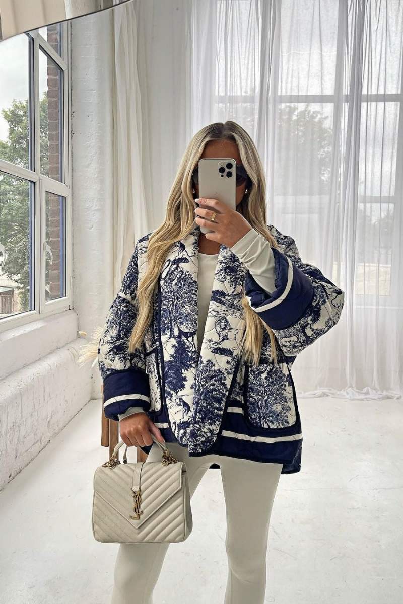 Women's oversized quilted jacket featuring a navy and white toile scenic print, open front, and contrast striped borders on the wide sleeves and hem.