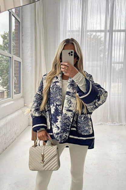 Women's oversized quilted jacket featuring a navy and white toile scenic print, open front, and contrast striped borders on the wide sleeves and hem.