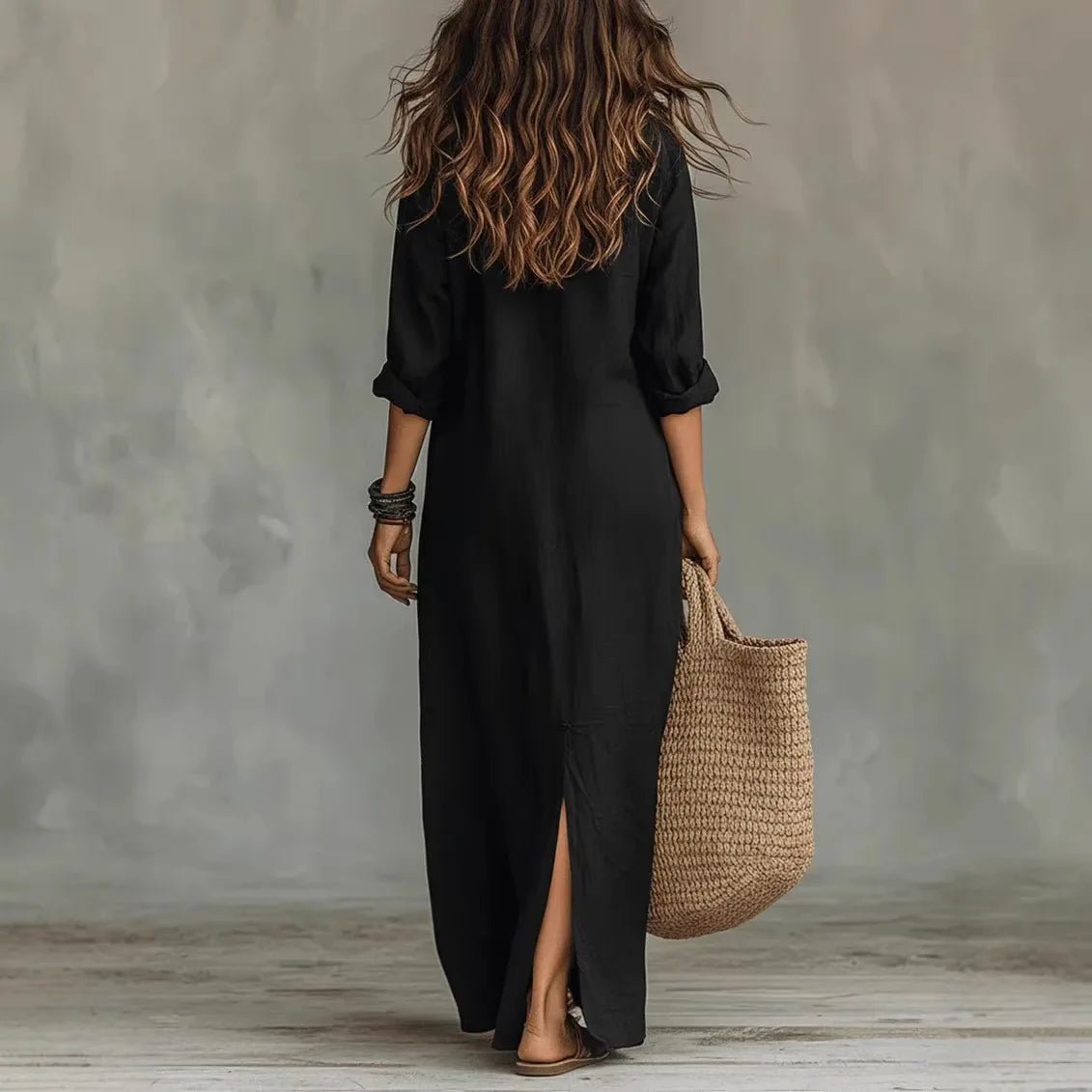 Black - A woman wearing a relaxed-fit white linen maxi sundress with a pointed collar, button placket, and front slit, carrying a woven straw bag.