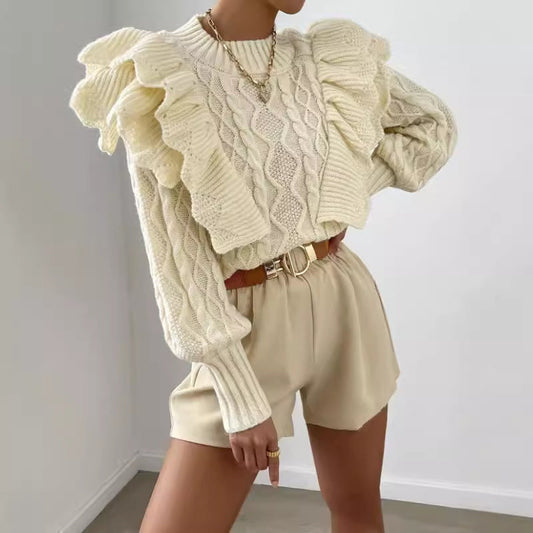 Off White - Women's cream chunky cable knit sweater featuring dramatic oversized ruffles on the shoulders and a ribbed crew neckline, styled with beige shorts and a brown belt.
