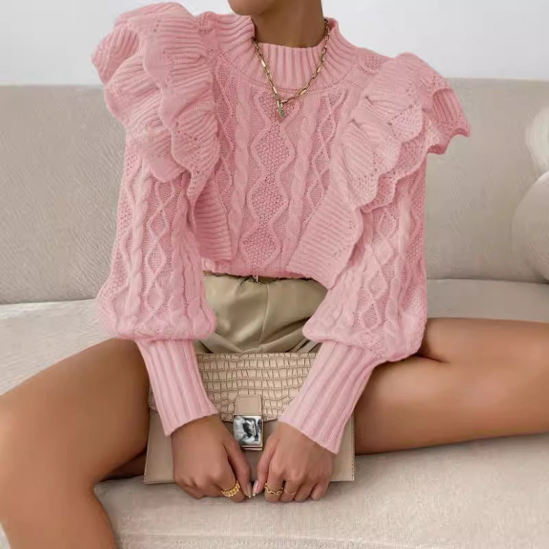 Pink - Women's cream chunky cable knit sweater featuring dramatic oversized ruffles on the shoulders and a ribbed crew neckline, styled with beige shorts and a brown belt.