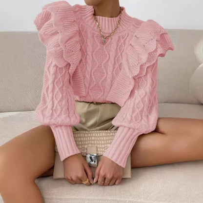 Pink - Women's cream chunky cable knit sweater featuring dramatic oversized ruffles on the shoulders and a ribbed crew neckline, styled with beige shorts and a brown belt.