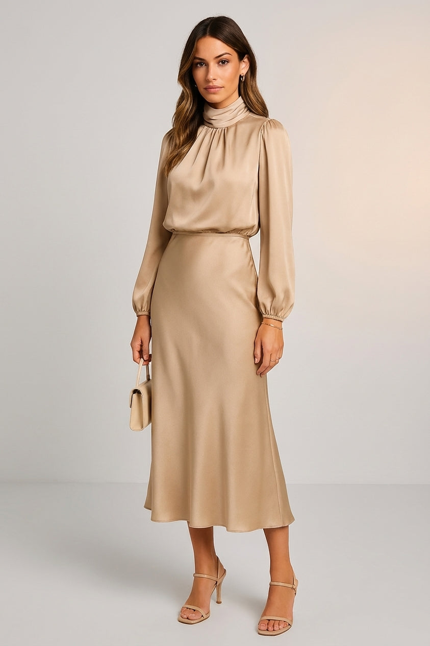 Beige - A woman wearing a champagne-coloured satin midi dress with a high neckline, long balloon sleeves, and an elasticated waist, posing against a neutral grey background.