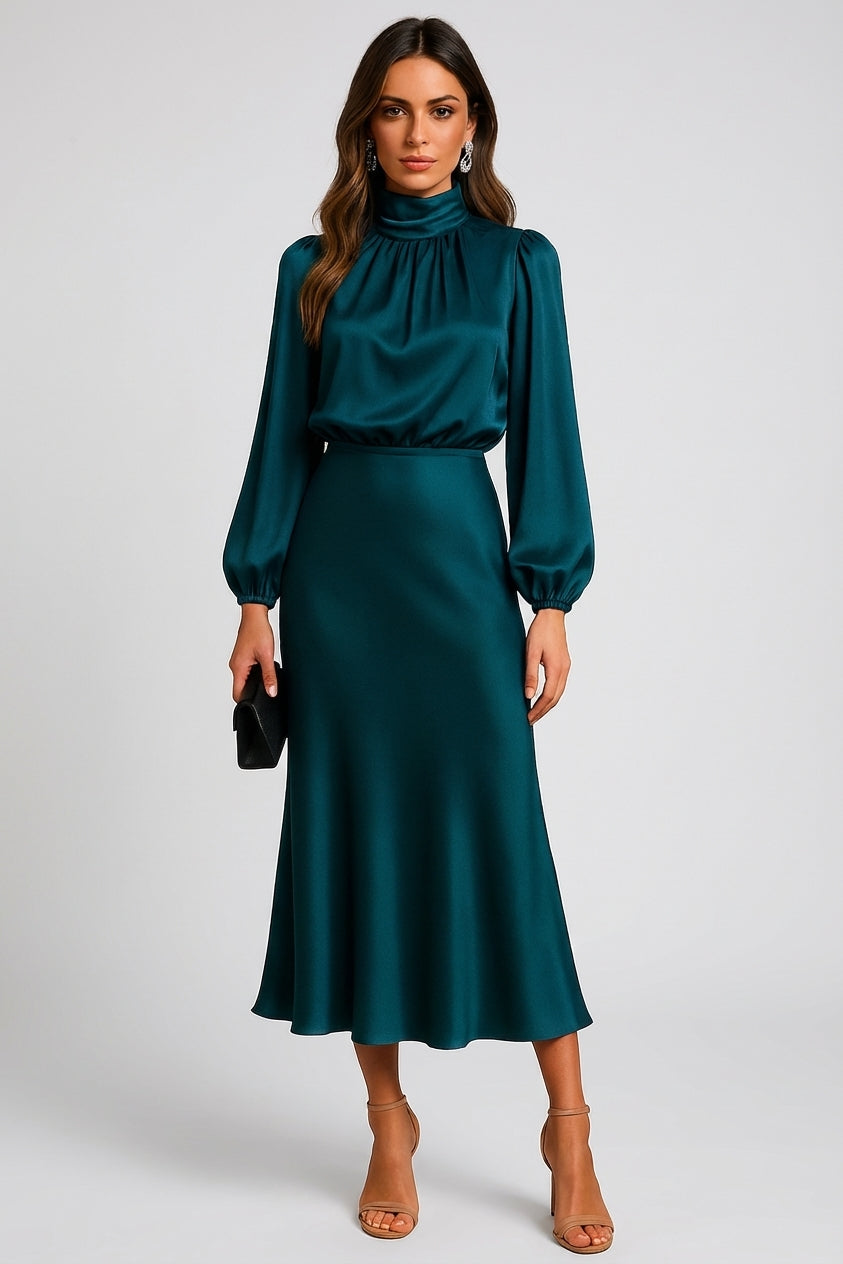 Teal Blue - A woman wearing a champagne-coloured satin midi dress with a high neckline, long balloon sleeves, and an elasticated waist, posing against a neutral grey background.
