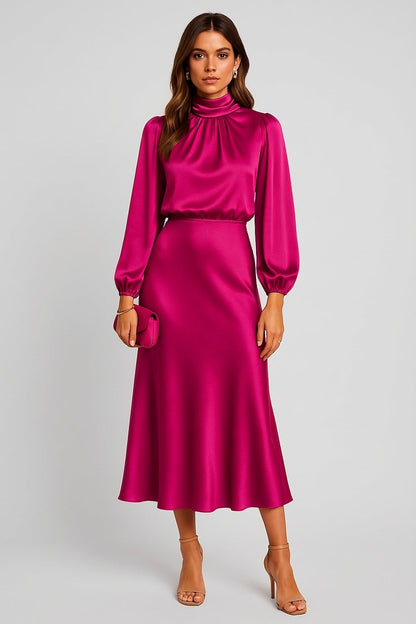 Hot Pink - A woman wearing a champagne-coloured satin midi dress with a high neckline, long balloon sleeves, and an elasticated waist, posing against a neutral grey background.