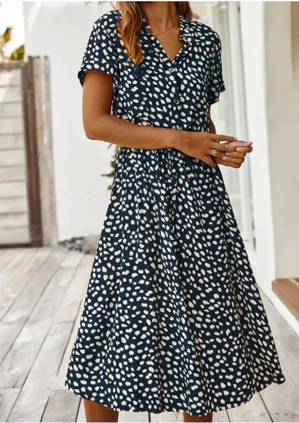 Deep Blue - Woman wearing a white midi shirt dress with a brown abstract spotted print, featuring a collared button-front bodice and a drawstring waist.