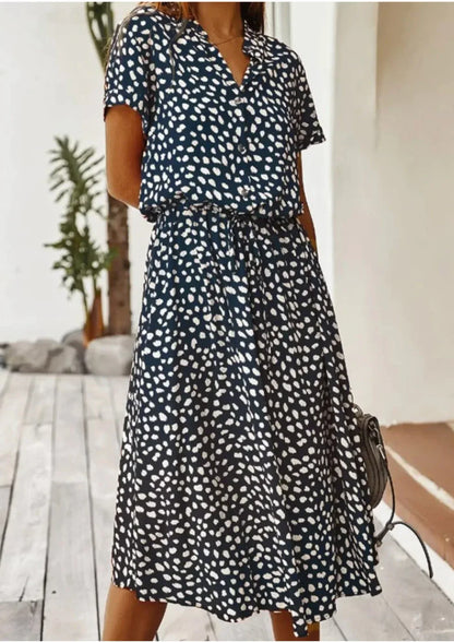 Deep Blue - Woman wearing a white midi shirt dress with a brown abstract spotted print, featuring a collared button-front bodice and a drawstring waist.