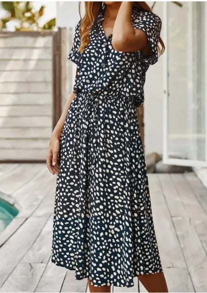 Deep Blue - Woman wearing a white midi shirt dress with a brown abstract spotted print, featuring a collared button-front bodice and a drawstring waist.