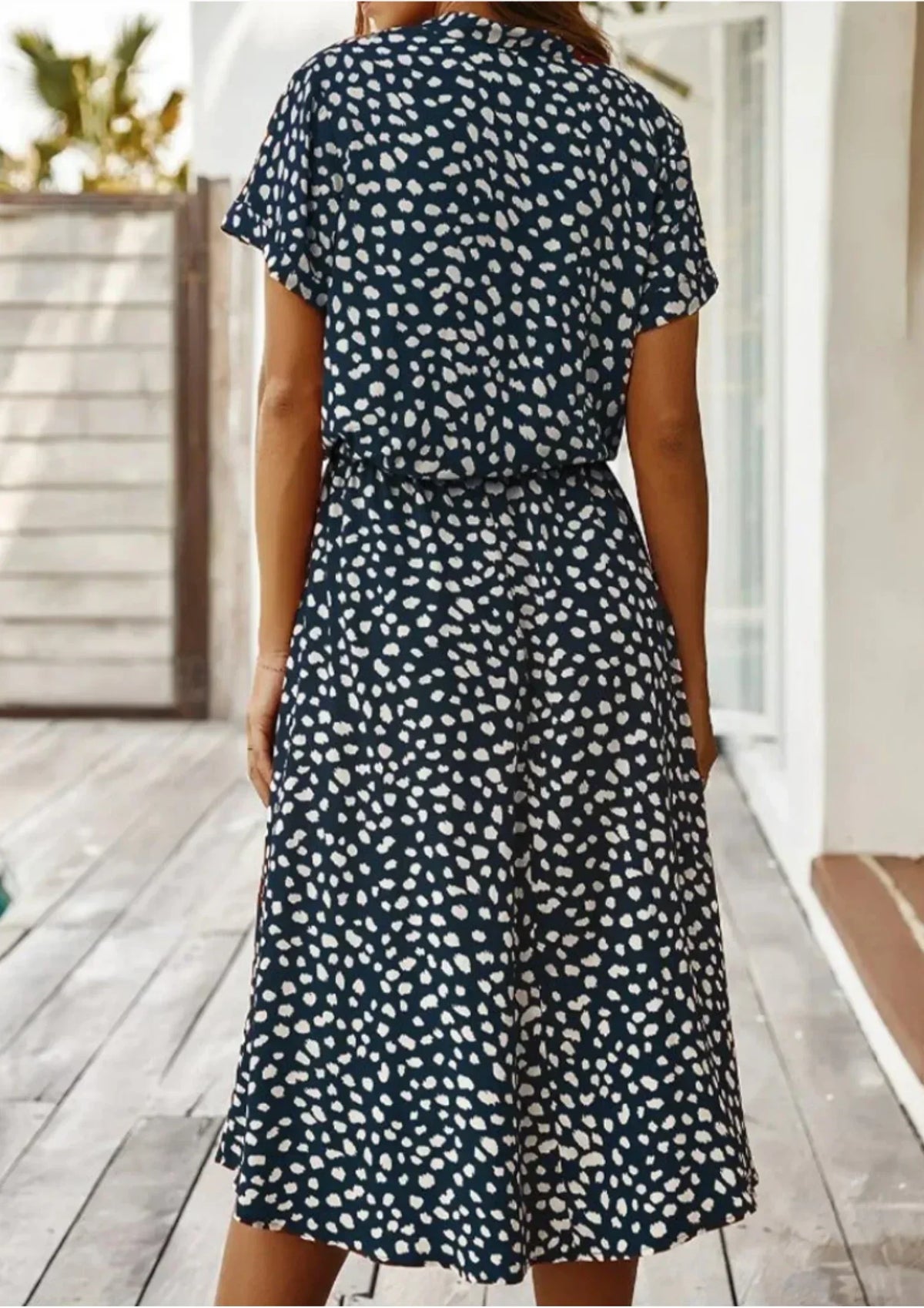 Deep Blue - Woman wearing a white midi shirt dress with a brown abstract spotted print, featuring a collared button-front bodice and a drawstring waist.
