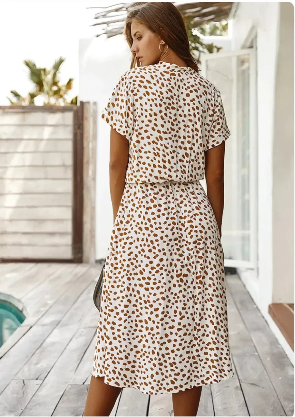 Light brown - Woman wearing a white midi shirt dress with a brown abstract spotted print, featuring a collared button-front bodice and a drawstring waist.