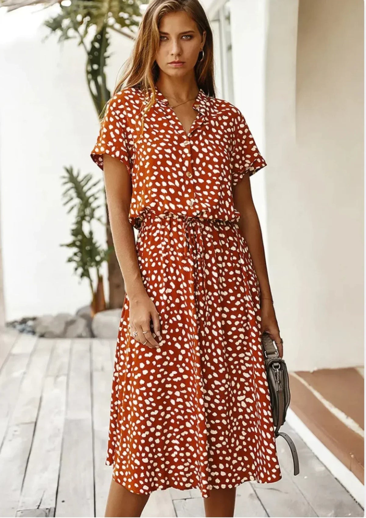 Red Orange - Woman wearing a white midi shirt dress with a brown abstract spotted print, featuring a collared button-front bodice and a drawstring waist.