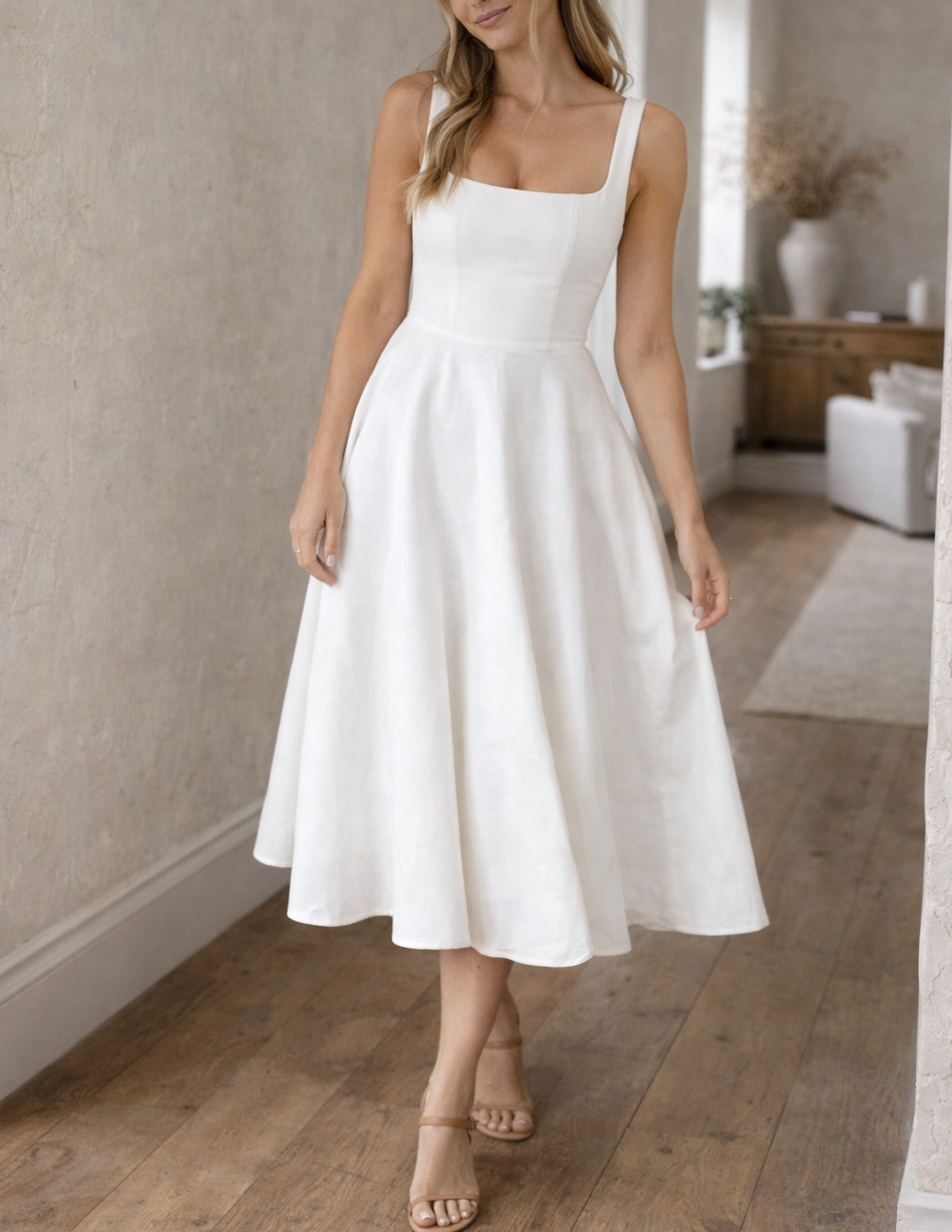 White - A woman wearing a structured white textured crepe midi dress with a square neckline, wide straps, a fitted bodice, and a voluminous A-line skirt with side pockets.