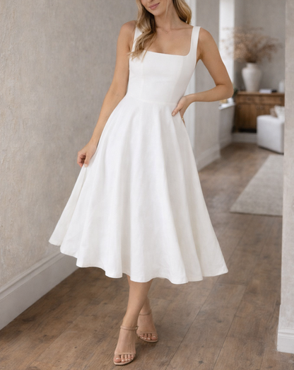 Black - A woman wearing a structured white textured crepe midi dress with a square neckline, wide straps, a fitted bodice, and a voluminous A-line skirt with side pockets.