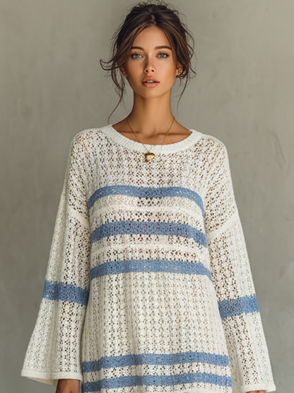 White - A person wearing a cream and blue striped open-knit crochet mini dress with wide long sleeves, holding a woven tote bag.