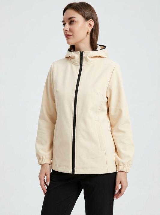 White - A woman wearing a cream-coloured structured hooded jacket with a contrast black front zipper, elasticised cuffs, and side pockets, paired with black pants.
