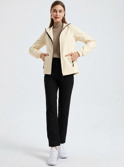 White - A woman wearing a cream-coloured structured hooded jacket with a contrast black front zipper, elasticised cuffs, and side pockets, paired with black pants.