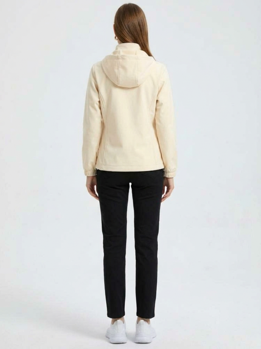 White - A woman wearing a cream-coloured structured hooded jacket with a contrast black front zipper, elasticised cuffs, and side pockets, paired with black pants.