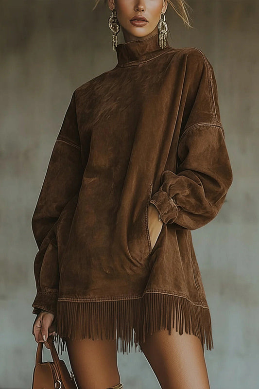 Model wearing a relaxed fit faux-suede mini dress featuring a high turtleneck, dropped long sleeves, front pockets, and a long fringe hemline.