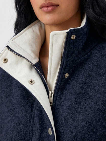 Navy - A woman wearing a dark navy blue textured jacket with a high stand collar lined in contrast cream fleece, featuring a snap-button front closure and a relaxed fit.