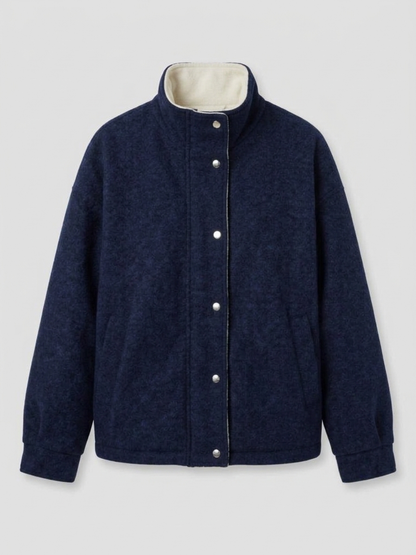Navy - A woman wearing a dark navy blue textured jacket with a high stand collar lined in contrast cream fleece, featuring a snap-button front closure and a relaxed fit.