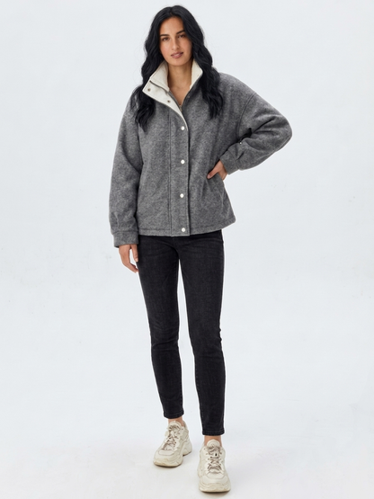 Gray - A woman wearing a dark navy blue textured jacket with a high stand collar lined in contrast cream fleece, featuring a snap-button front closure and a relaxed fit.