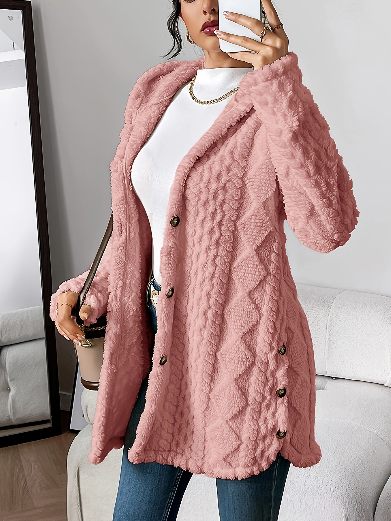 Dark Pink - A woman wearing a beige, mid-length textured fleece hooded jacket with a diamond pattern, button closure, and buttoned side vents, layered over a white high-neck top and blue jeans.