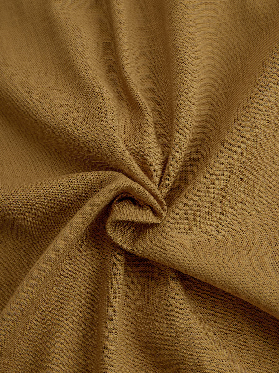 Mustard - A woman wearing a mustard-coloured, long-sleeve midi shirt dress made of a textured fabric. The dress features a pointed collar, button-down front, and a matching fabric tie belt at the waist.