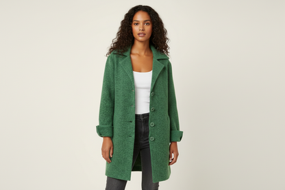 Green - A woman wearing a textured green mid-length coat with a notch lapel, single-breasted buttons, and cuffed sleeves, styled over a white top and dark grey jeans.