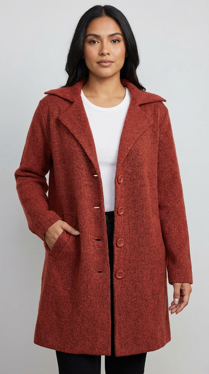 Red - A woman wearing a textured green mid-length coat with a notch lapel, single-breasted buttons, and cuffed sleeves, styled over a white top and dark grey jeans.