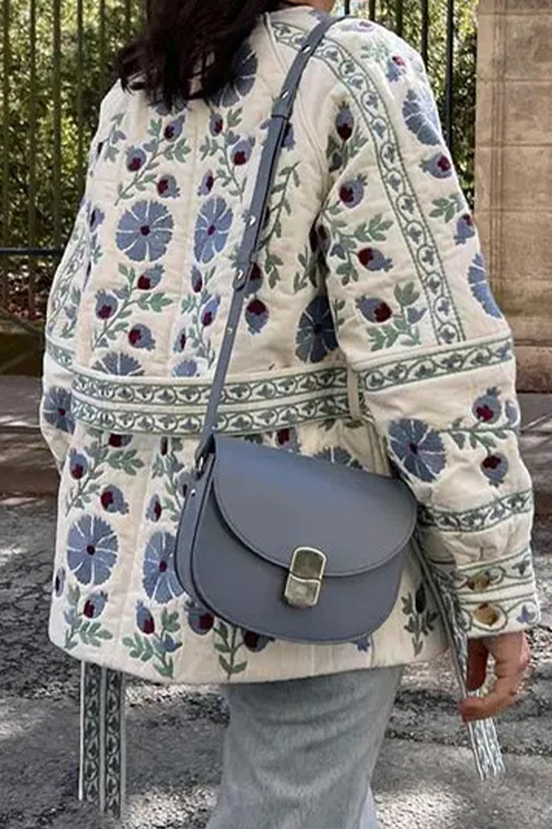 Blue - Women's cream mid-length jacket featuring blue and burgundy floral embroidery, a matching tie-waist belt, and button-front closure, styled over denim.