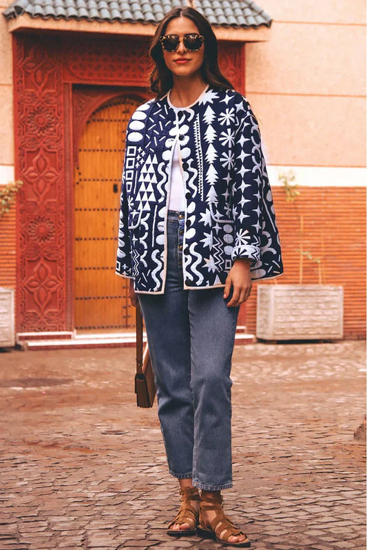 Dark Blue - Woman wearing a navy blue quilted open-front jacket with bold white abstract geometric embroidery, styled with jeans and sandals.