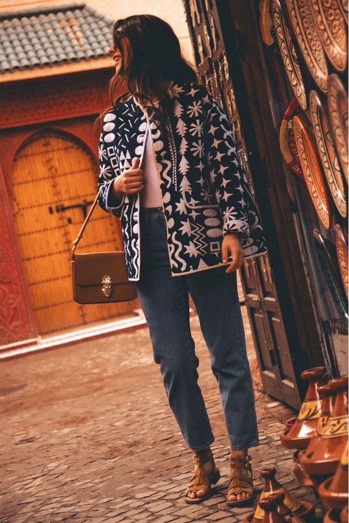 Dark Blue - Woman wearing a navy blue quilted open-front jacket with bold white abstract geometric embroidery, styled with jeans and sandals.