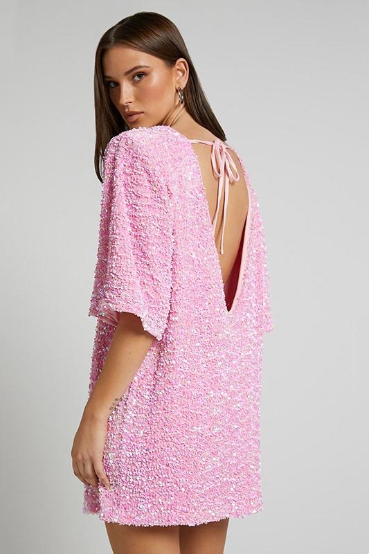 Woman wearing a pink sequin mini dress with open back