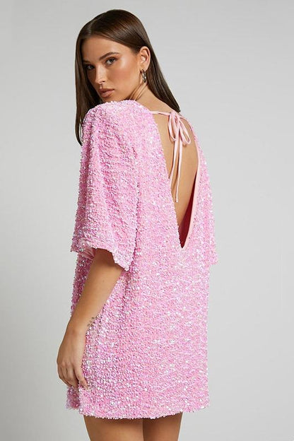 Woman wearing a pink sequin mini dress with open back