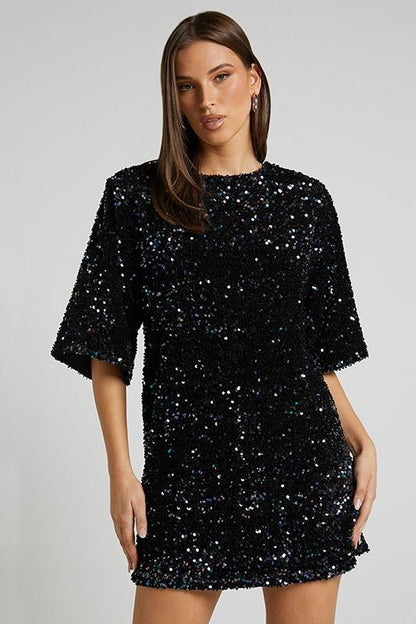 Woman wearing a pink sequin mini dress with open back
