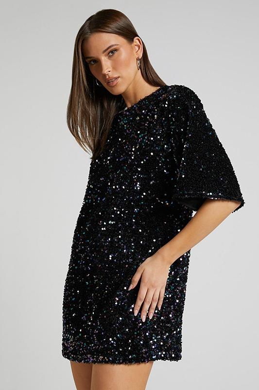Woman wearing a pink sequin mini dress with open back