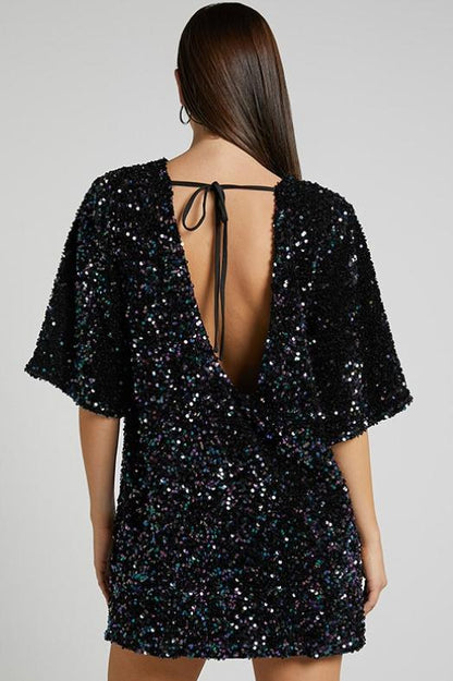 Woman wearing a pink sequin mini dress with open back