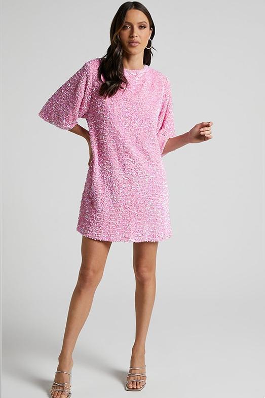 Woman wearing a pink sequin mini dress with open back