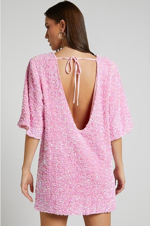 Woman wearing a pink sequin mini dress with open back