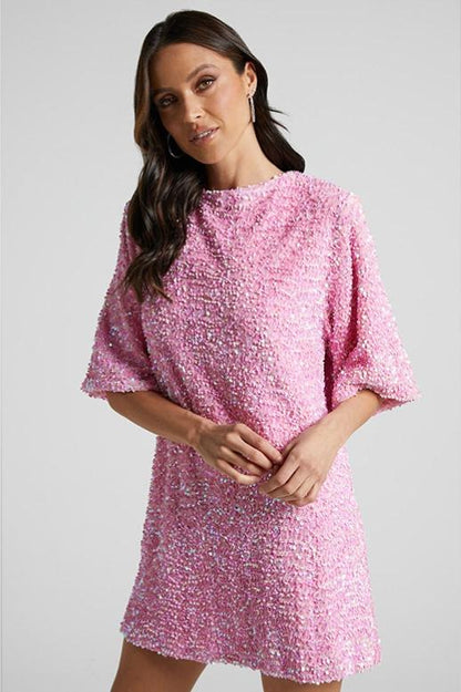 Woman wearing a pink sequin mini dress with open back