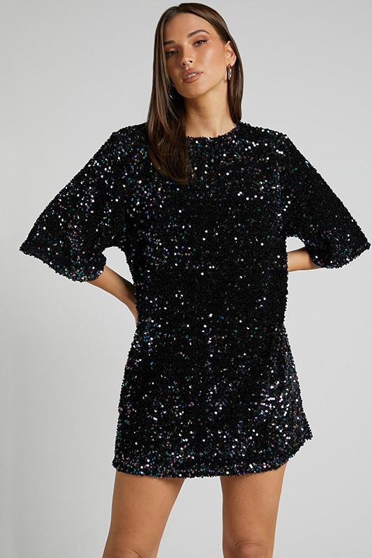 Woman wearing a pink sequin mini dress with open back