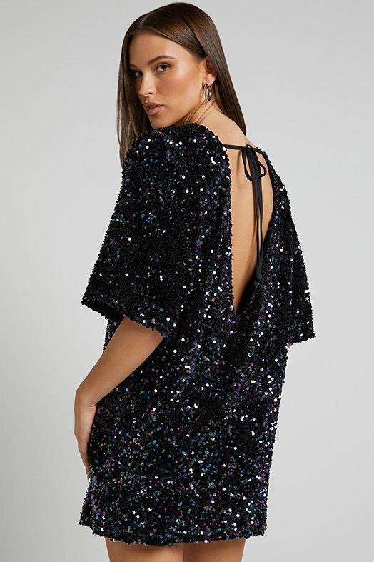 Woman wearing a pink sequin mini dress with open back