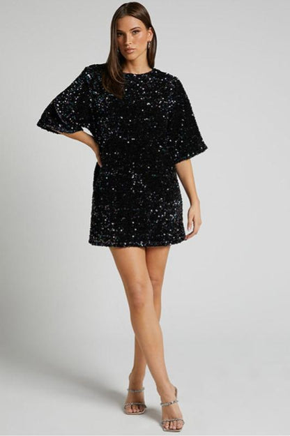 Woman wearing a pink sequin mini dress with open back